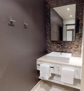 La salle de bains est pourvue d'un lavabo blanc et d'un miroir. dans l'établissement White Pearl Apartment 0.14, à Timmendorfer Strand