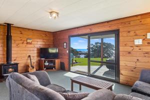 a living room with a couch and a tv and a fireplace at Airi Kainga - Seaside Escape in Te Kaha