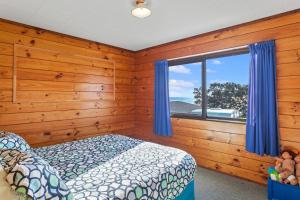 a bedroom with wooden walls and a bed and a window at Airi Kainga - Seaside Escape in Te Kaha
