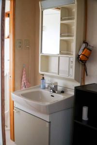a bathroom with a white sink and a mirror at guest house komoriya in Matsumoto