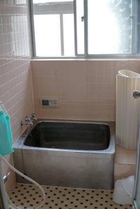 a bath tub in a bathroom with a window at guest house komoriya in Matsumoto