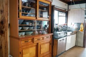 a kitchen with a wooden cabinet with dishes in it at guest house komoriya in Matsumoto