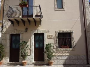 a building with two windows and a balcony with plants at B&B San Domenico in Realmonte