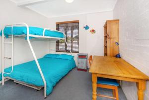 een slaapkamer met een stapelbed en een houten tafel bij Kendall Beach Apartments 5 - Belongil Beach in Byron Bay