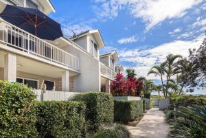 a large white house with bushes and trees at Kendall Beach Apartments 5 - Belongil Beach in Byron Bay