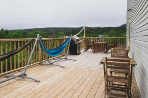 a deck with a hammock and a table and chairs at Out East Adventure Centre in Rocky Harbour
