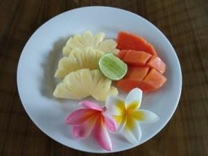a plate of food with fruit and flowers on a table at Villa Ava Seminyak Bali in Seminyak