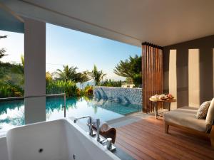 a bathroom with a bath tub and a swimming pool at Anantara Uluwatu Bali Resort in Uluwatu