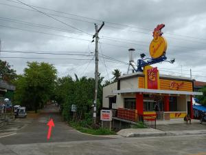 a building with a chicken sign on it next to a street at Touristlink Homestay in Donsol