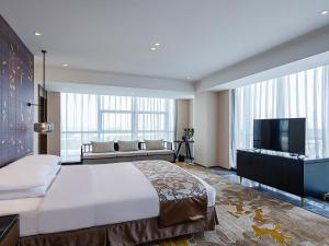 um quarto com uma cama grande e uma televisão de ecrã plano em Grand Metropark Hotel Chongqing em Chongqing