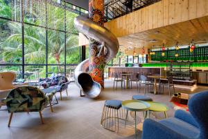 a restaurant with a slide and tables and chairs at TOOJOU Kota Kinabalu - Travel Meets Social in Kota Kinabalu