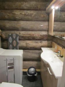 a bathroom with a wooden wall with a toilet and sink at Rukakaiku Cottages in Ruka