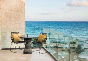 a table and chairs on a balcony with the ocean at Thompson Playa del Carmen Beach House, part of Hyatt in Playa del Carmen