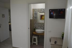 a bathroom with a sink and a tv on the wall at Casa Catalano in San Vito lo Capo