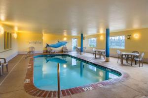 a pool in a hotel with tables and chairs at Bend Quality Inn in Bend