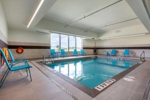 une grande piscine avec des chaises bleues dans un bâtiment dans l'établissement Comfort Inn & Suites, à Napanee
