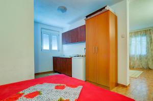 a small kitchen with a red bed and a red blanket at Apartments Radost in Utjeha