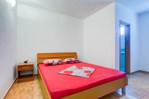 - une chambre avec un lit rouge et une couverture rouge dans l'établissement Apartments Radost, à Utjeha-Bušat