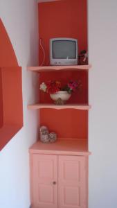 a tv sitting on a shelf in a room at Vocamvilia Apartments in Kamari