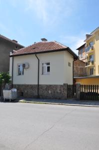 a white house with a fence next to a street at Къща за гости Ирис in Kyustendil