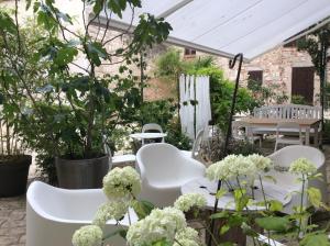een groep witte stoelen en tafels in een tuin bij La maison sur la place in Penne-dʼAgenais