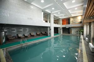 a swimming pool in a hotel with chairs and tables at The Corporate Hotel and Convention Centre in Ulaanbaatar
