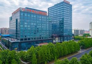 a large glass building with trees in front of it at CYTS Eastern Jiading Hotel Shanghai - Original CYTS GreenTree Eastern International Hotel in Jiading