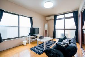 uma sala de estar com um sofá e 2 janelas grandes em Murata Corpo 301 em Tóquio