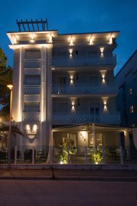 Un grand bâtiment blanc avec des lumières sur lui dans l'établissement Hotel Vela D'Oro, à Riccione
