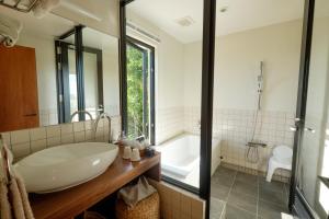 a bathroom with a large white sink and a tub at Kaiza in Nanjo