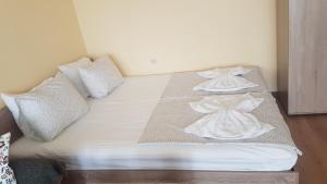 uma cama com lençóis brancos e almofadas em Апартамент за нощувки em Gotse Delchev