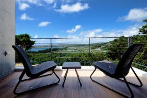 two chairs and a table on a balcony with a view at Kaiza in Nanjo