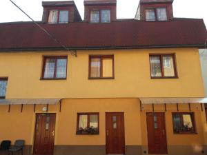 uma casa amarela com portas e janelas vermelhas em Ubytovňa Tavros em Žilina