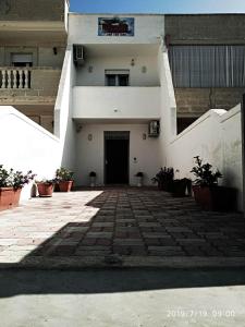a white building with a black door and some plants at Bed Daniele in Torricella