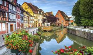 einen Kanal in einer Stadt mit Häusern und Blumen in der Unterkunft Appartement grand standing VAUBAN 10 Personnes centre historique de Colmar in Colmar