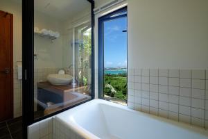 a bathroom with a large tub with a window at Kaiza in Nanjo