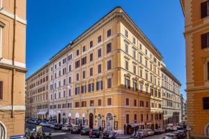 un grand bâtiment jaune avec des voitures garées devant lui dans l'établissement Hotel Sonya, à Rome