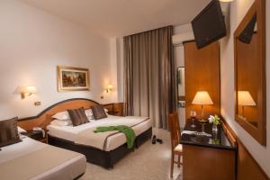 a hotel room with two beds and a television at Hotel Sonya in Rome