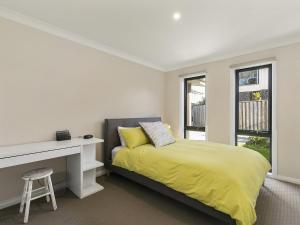 a white bedroom with a bed and a desk at SUMMER BREEZE FREE WIFI & NETFLIX INLET SIDE CENTRAL LOCATION in Inverloch
