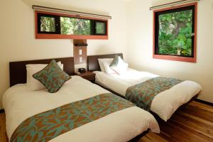a hotel room with two beds and two windows at Kaiza in Nanjo