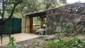 a patio with a stone wall and a table and chair at Maisonnette du berger de Croccano in Sartène