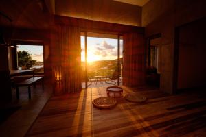 a living room with the sun shining through the windows at Kaiza in Nanjo