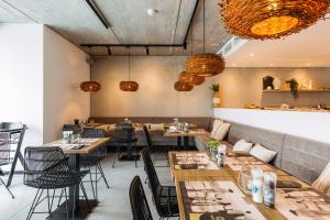 a dining room with tables and chairs and chandeliers at C-Hotels Zeegalm in Middelkerke
