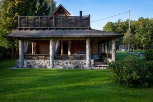 a log cabin with a balcony on a green lawn at Erlendi Kodumajutus in Pärnu