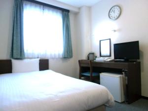 ein Hotelzimmer mit einem Bett, einem Schreibtisch und einer Uhr in der Unterkunft Hotel Green Line in Sendai