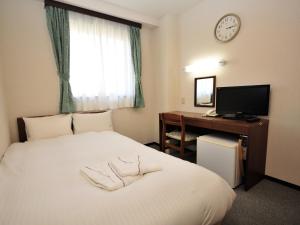 ein Hotelzimmer mit einem Bett, einem Schreibtisch und einer Uhr in der Unterkunft Hotel Green Line in Sendai