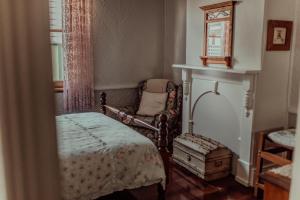 a bedroom with a bed and a chair and a window at Railway Cottage in Bunbury