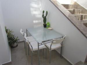 een eettafel met witte stoelen en een cactus bij Eleni apartment Eilat in Eilat
