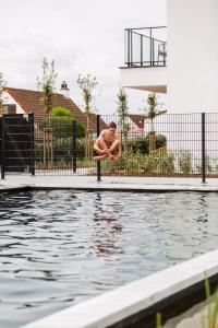 a man sitting on a pole next to a swimming pool at Zeegalm Bungalows in Middelkerke