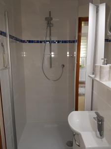 a white bathroom with a shower and a sink at Ferienwohnung am Rennsteig bei Eisenach - Ilona Schmidt in Wolfsburg-Unkeroda